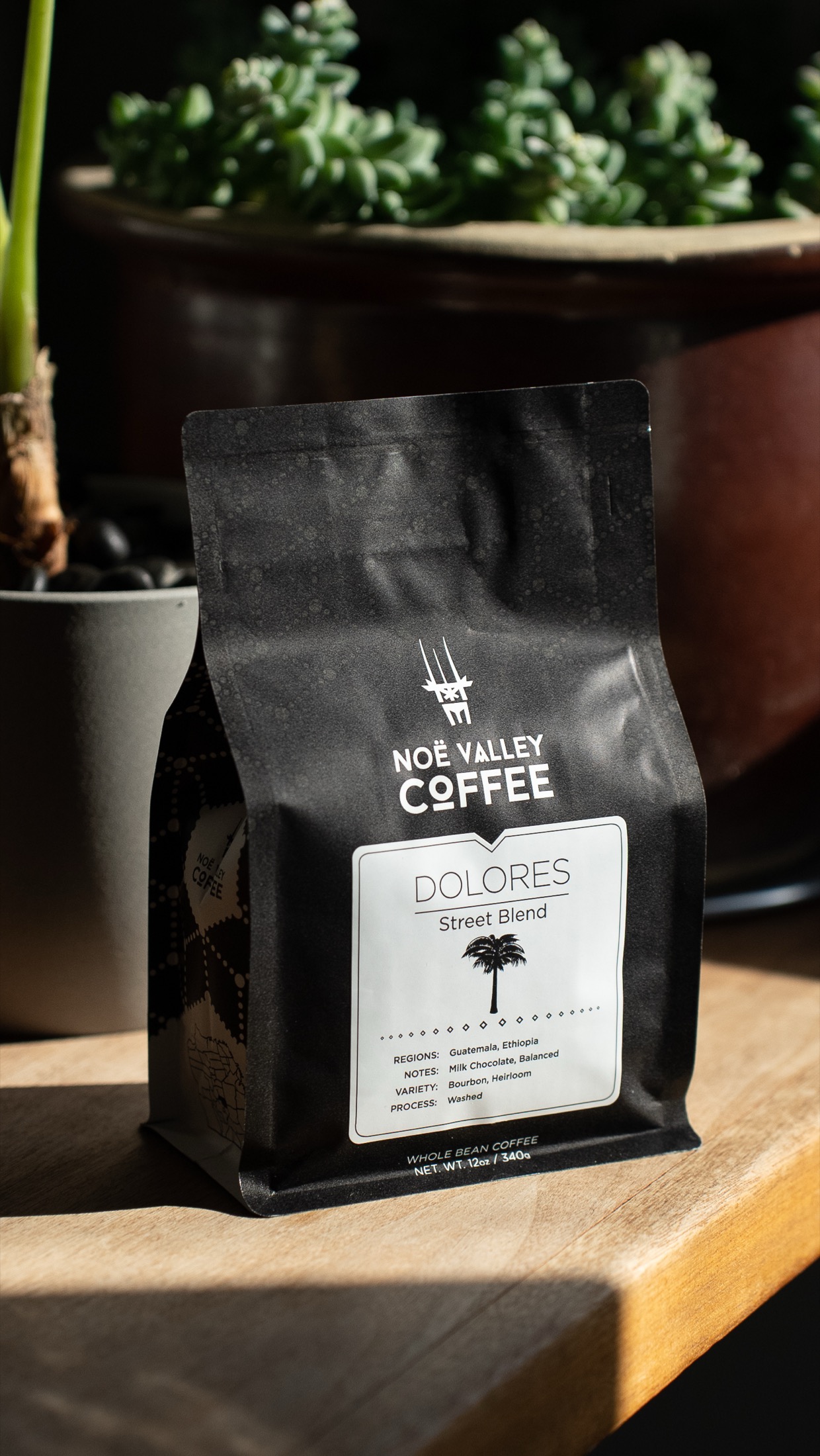 A 12 ounce bag of Noe Valley Coffee Dolores Street Blend on a cafe table.
